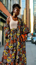 Woman wearing a colorful patterned outfit in a room with art on the walls.